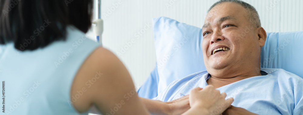 Fototapeta premium Cheerful asian nurse smiling and talking with elderly patient in the room.