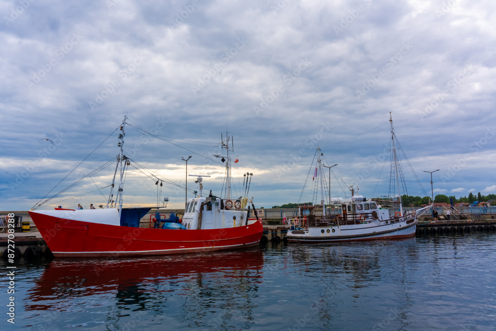 Pleasure boat is moored at the pier. Gray sky in the background. Beautiful tranquil seascape. Excursion tourism. High quality photo Pleasure boat is moored at the pier. Gray sky in the background. Beautiful tranquil seascape. Excursion tourism. High quality photo