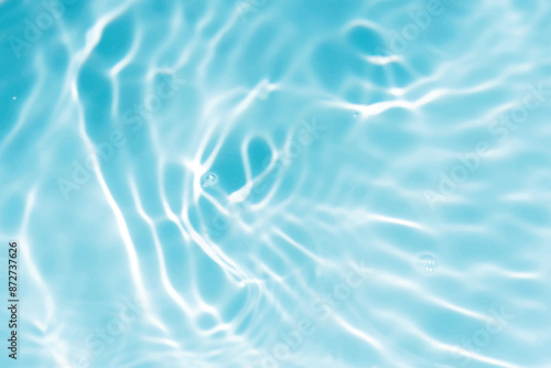 Blue water with ripples on the surface. Defocus blurred transparent blue colored clear calm water surface texture with splashes and bubbles. Water waves with shining pattern texture background.