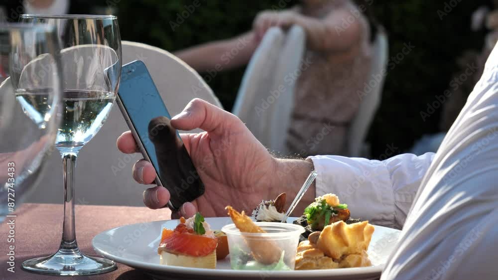 hand of a man using a mobile phone, reading a phone message and viewing news on the Internet while sitting in a restaurant hand of a man using a mobile phone, reading a phone message and viewing news on the Internet while sitting in a restaurant