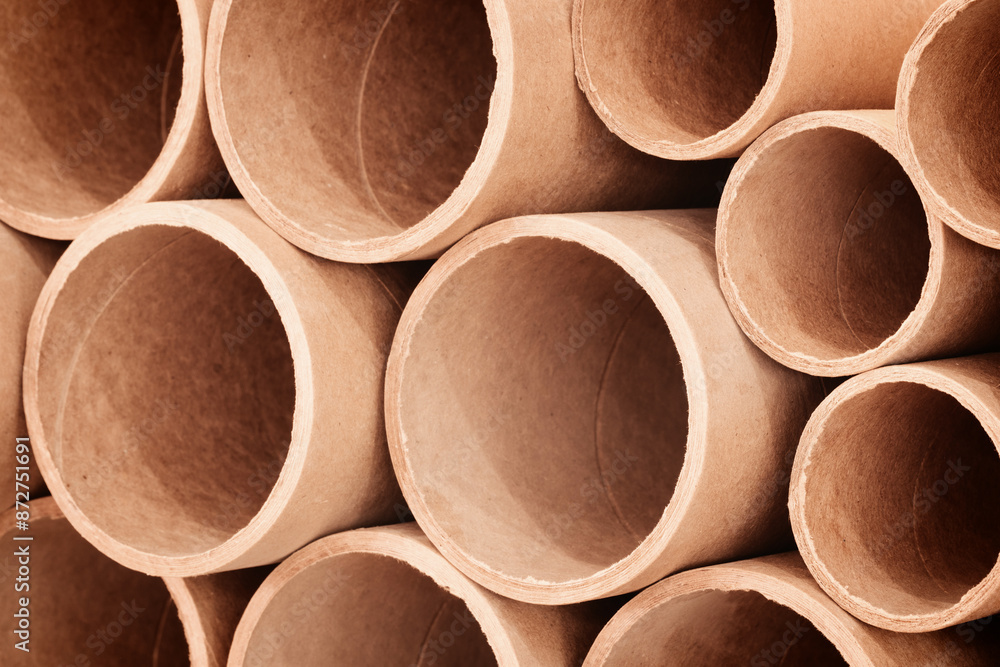 A stack of cardboard tubes as background. The tubes are brown and are arranged in a row A stack of cardboard tubes as background. The tubes are brown and are arranged in a row