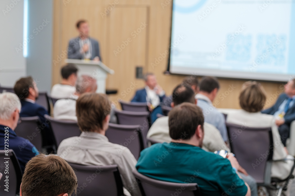 Group of business professionals attending a tech conference, listening to a presentation. Engaged audience seated in a modern conference room. Group of business professionals attending a tech conference, listening to a presentation. Engaged audience seated in a modern conference room.