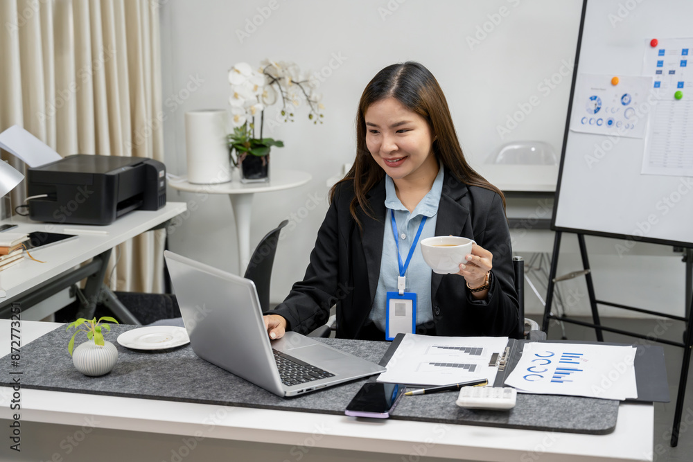 Asian businesswoman in a business suit is standing and working on her laptop at her desk in the office. businesspeople concept Asian businesswoman in a business suit is standing and working on her laptop at her desk in the office. businesspeople concept