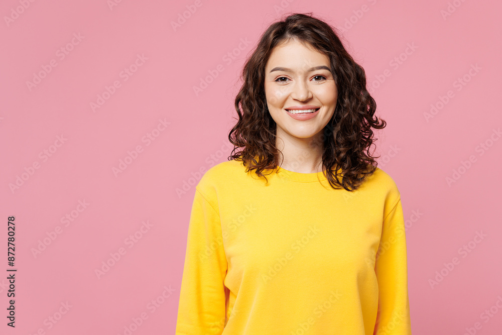 Young smiling happy cheerful satisfied fun cool woman wearing yellow sweatshirt casual clothes looking camera isolated on pastel light pink color background studio portrait. People lifestyle concept. Young smiling happy cheerful satisfied fun cool woman wearing yellow sweatshirt casual clothes looking camera isolated on pastel light pink color background studio portrait. People lifestyle concept.