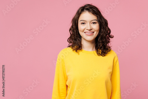Young smiling happy cheerful satisfied fun cool woman wearing yellow sweatshirt casual clothes looking camera isolated on pastel light pink color background studio portrait. People lifestyle concept. © ViDi Studio