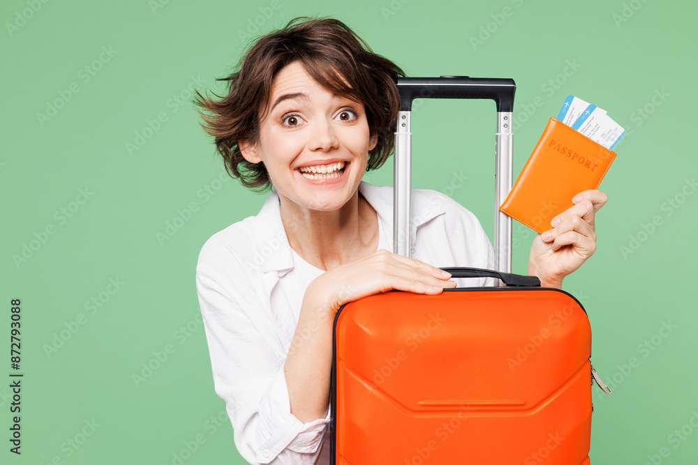 Close up traveler happy woman wear casual clothes hold passport ticket suitcase bag isolated on plain green background. Tourist travel abroad in free spare time rest getaway. Air flight trip concept. Close up traveler happy woman wear casual clothes hold passport ticket suitcase bag isolated on plain green background. Tourist travel abroad in free spare time rest getaway. Air flight trip concept.