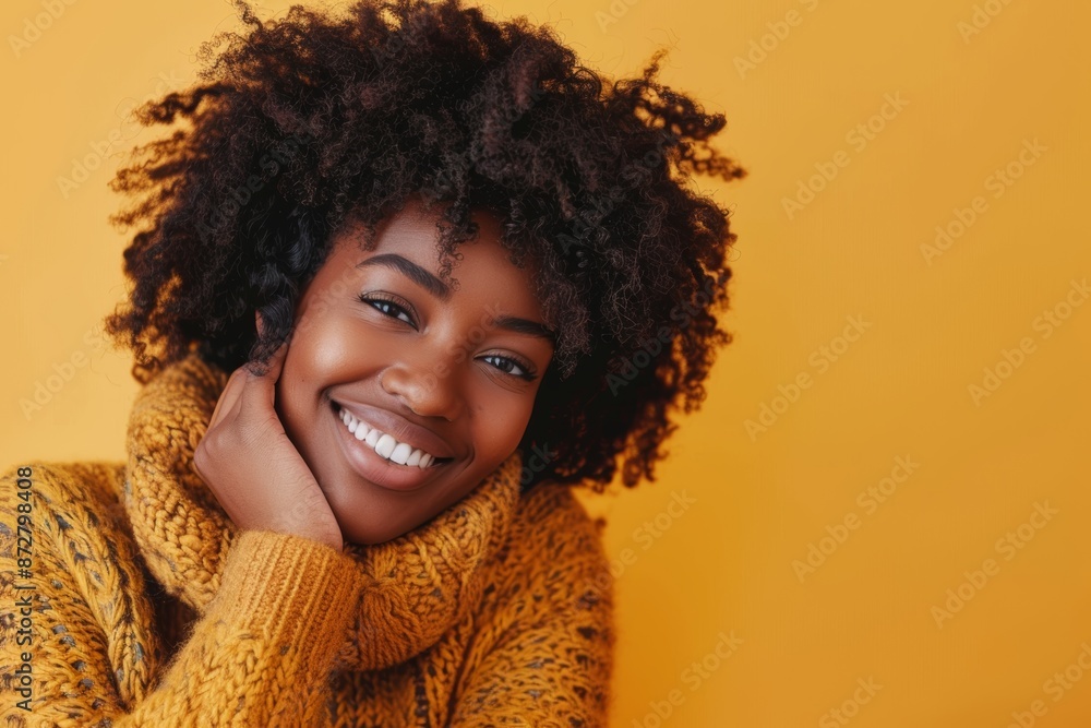 Portrait of a glad afro-american woman in her 30s dressed in a warm wool sweater in front of pastel yellow background Portrait of a glad afro-american woman in her 30s dressed in a warm wool sweater in front of pastel yellow background