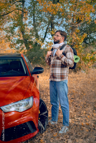 An adventurer with a backpack stands by his car, arriving at a camping site, showcasing tours and guides for various destinations.