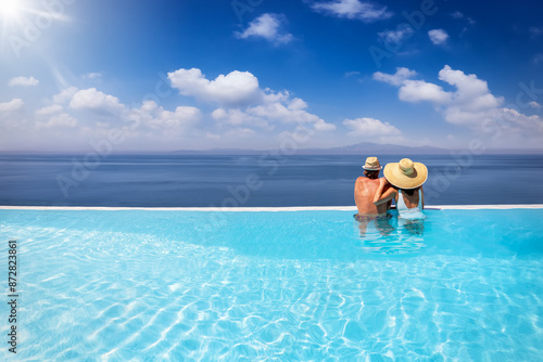 Photography A holiday couple in a big infinity pool enjoys the panoramic view to the blue se