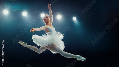 Obraz na płótnie Elegant Ballet Dancing Ballerina White in Tutu Executes Flawless Grand Jeté Under Bright Stage Lights, Capturing the Grace and Precision of Classical Ballet in Stunning Performance