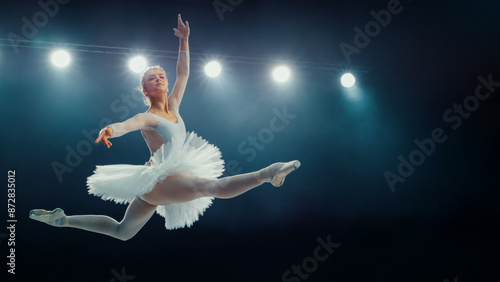 Obraz na płótnie Graceful Ballet Dancing Ballerina in White Tutu Performs Stunning Grand Jeté Under Stage Lights, Her Elegance and Athleticism in Captivating Ballet Performance