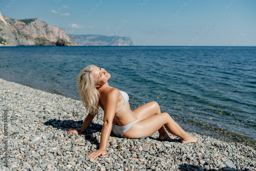 A woman is laying on the beach, enjoying the sun and the ocean A woman is laying on the beach, enjoying the sun and the ocean