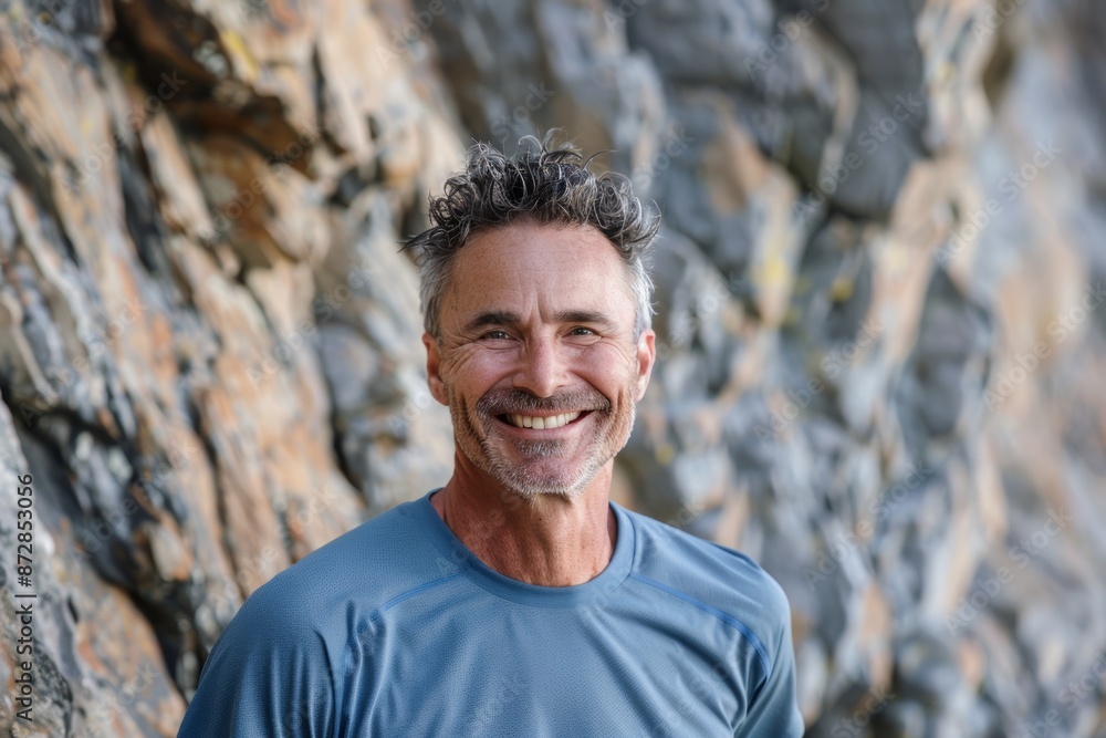 Portrait of a smiling caucasian man in his 40s wearing a moisture-wicking running shirt in front of rocky cliff background Portrait of a smiling caucasian man in his 40s wearing a moisture-wicking running shirt in front of rocky cliff background