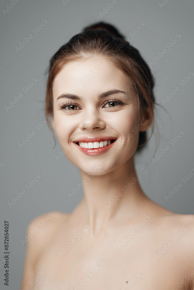Young woman with a beautiful smile posing on a grey background, isolated on white Young woman with a beautiful smile posing on a grey background, isolated on white