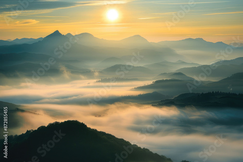 A misty mountain range with layers of fog and a rising sun