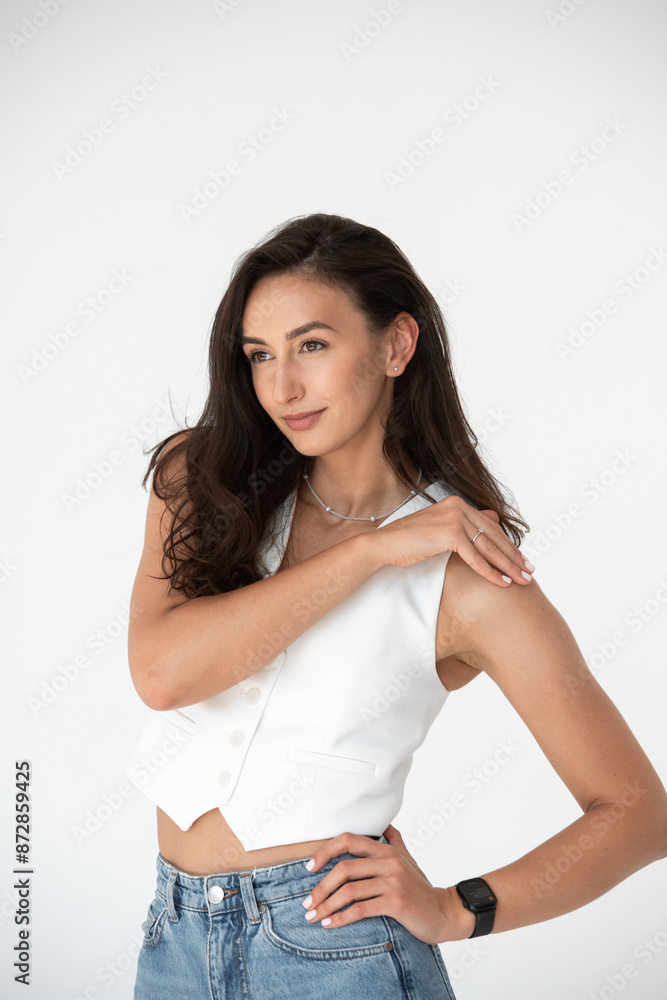 Happy beautiful girl posing in a new hot summer look. Wearing blue jeans and white waistcoat Happy beautiful girl posing in a new hot summer look. Wearing blue jeans and white waistcoat