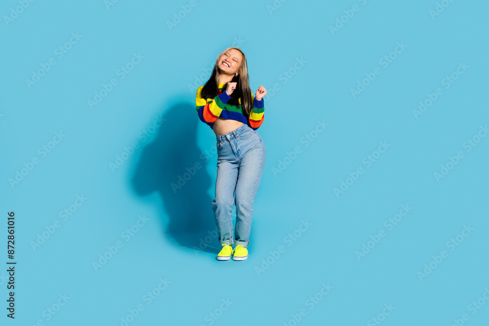 Full size photo of pretty young girl dancing have fun enjoy disco wear trendy striped outfit isolated on blue color background Full size photo of pretty young girl dancing have fun enjoy disco wear trendy striped outfit isolated on blue color background