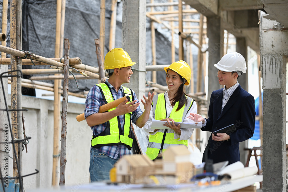 A team of construction professionals in safety hard hats planning development details at construction site A team of construction professionals in safety hard hats planning development details at construction site