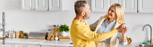 A mature man holds a woman lovingly in a cozy kitchen setting at home. photo