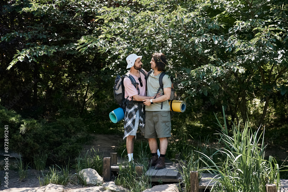 A young gay couple hikes through a lush forest in the summertime. A young gay couple hikes through a lush forest in the summertime.