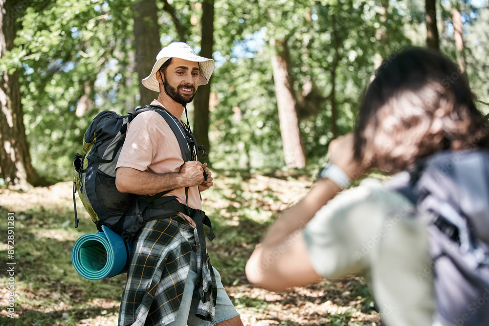 A young gay couple hikes through a lush forest on a sunny summer day. A young gay couple hikes through a lush forest on a sunny summer day.