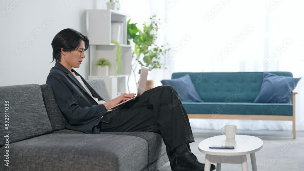 リビングでノートパソコンを使う男性 リビングでノートパソコンを使う男性