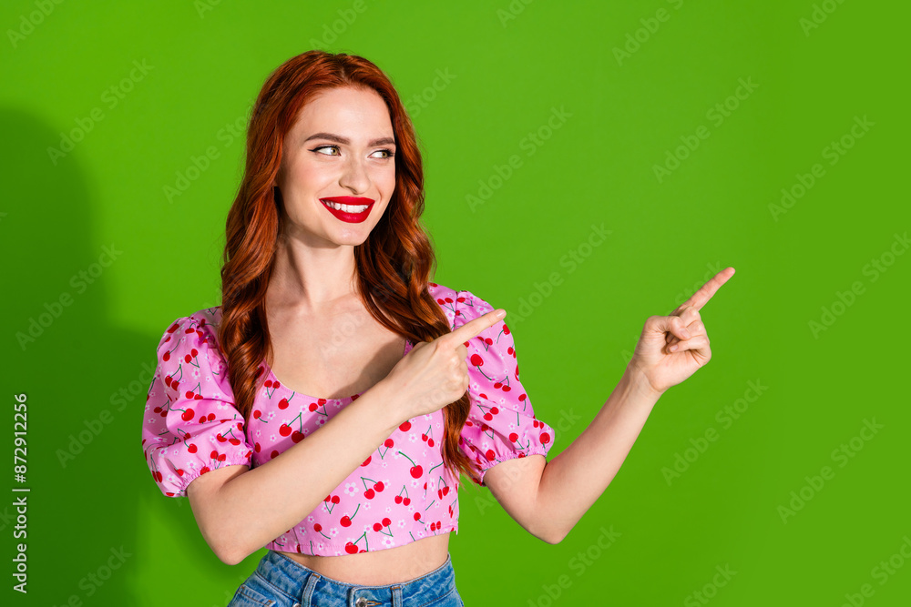 Photo of shiny attractive lady dressed print top showing two fingers empty space isolated green color background Photo of shiny attractive lady dressed print top showing two fingers empty space isolated green color background