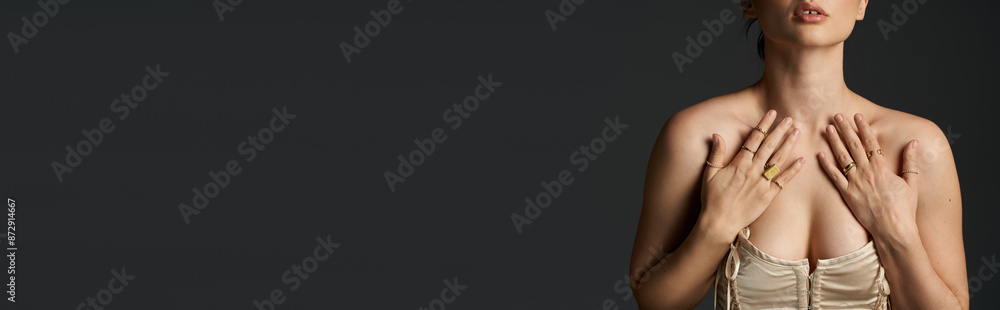 Fototapeta premium A young woman with dark hair shows off her golden rings on a dark background.