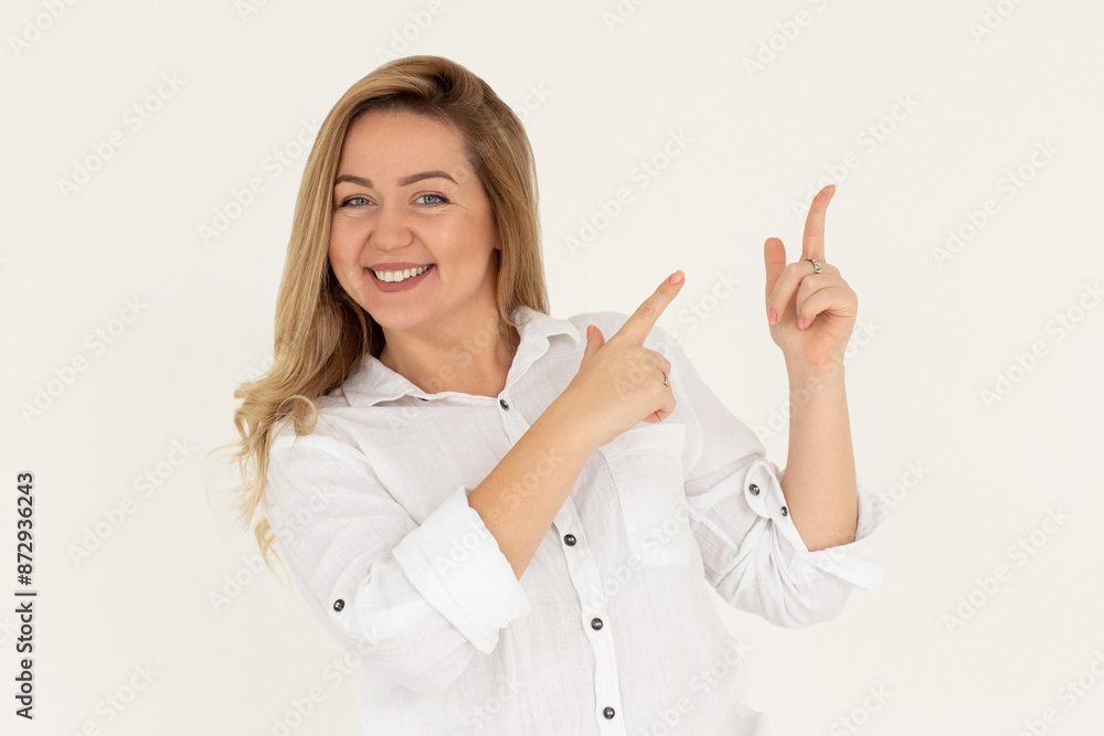 Young confident woman showing logo on empty space. Smiling girl inviting or advertising promo deal, pointing fingers right and looking at camera, white background. Young confident woman showing logo on empty space. Smiling girl inviting or advertising promo deal, pointing fingers right and looking at camera, white background.