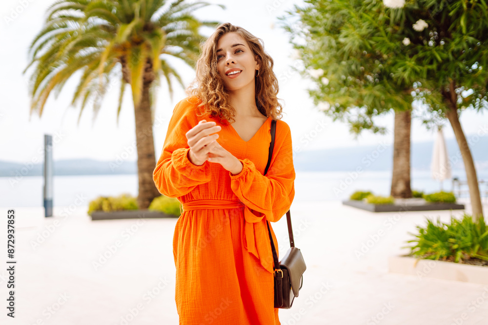 Fototapeta premium Beautiful woman in summer dress walking along the street street city. Tropical climate. Concept of lifestyle, vacation, fashion, travel.