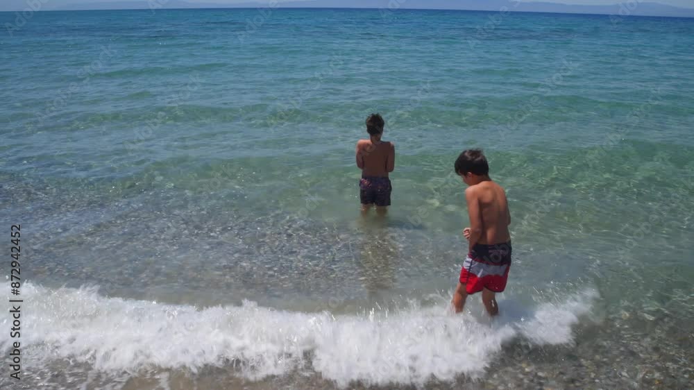 Two caucasian boys preparing to enter the sea at Kalamata ,Peloponnese, Greece, wide tilt up shot 4K Two caucasian boys preparing to enter the sea at Kalamata ,Peloponnese, Greece, wide tilt up shot 4K