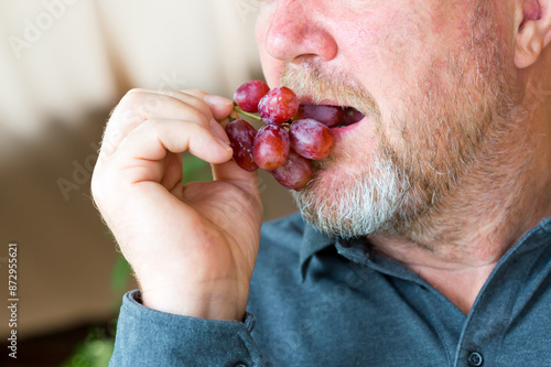 A man eating a fresh red grapes.