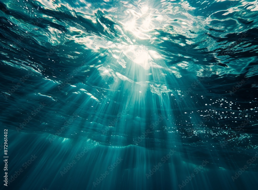 Sunlight beams through the clear blue water of a lake or ocean, creating a stunning reflection of the sun above. Sunlight beams through the clear blue water of a lake or ocean, creating a stunning reflection of the sun above.