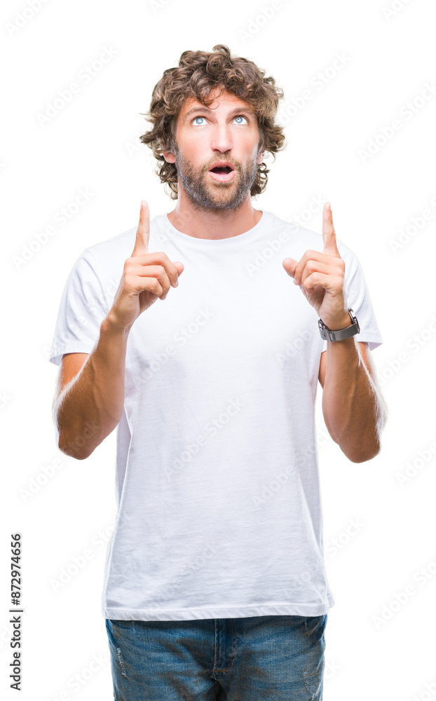 Fototapeta premium Handsome hispanic model man over isolated background amazed and surprised looking up and pointing with fingers and raised arms.