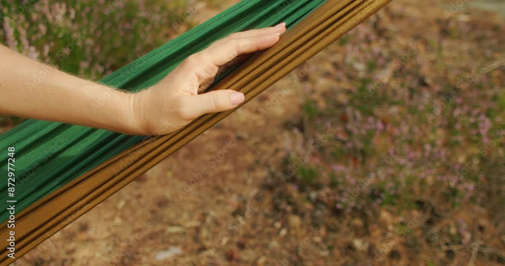 Close-up shot of relaxed hand lies on fabric hammock in a scenic outdoor setting with natural background. Close-up shot of relaxed hand lies on fabric hammock in a scenic outdoor setting with natural background.