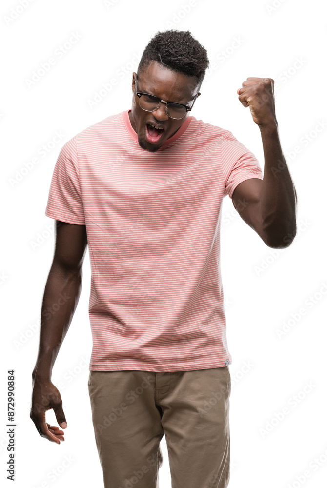 Young african american man wearing pink t-shirt angry and mad raising fist frustrated and furious while shouting with anger. Rage and aggressive concept. Young african american man wearing pink t-shirt angry and mad raising fist frustrated and furious while shouting with anger. Rage and aggressive concept.