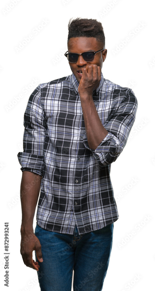 Young african american man wearing sunglasses over isolated background looking stressed and nervous with hands on mouth biting nails. Anxiety problem. Young african american man wearing sunglasses over isolated background looking stressed and nervous with hands on mouth biting nails. Anxiety problem.