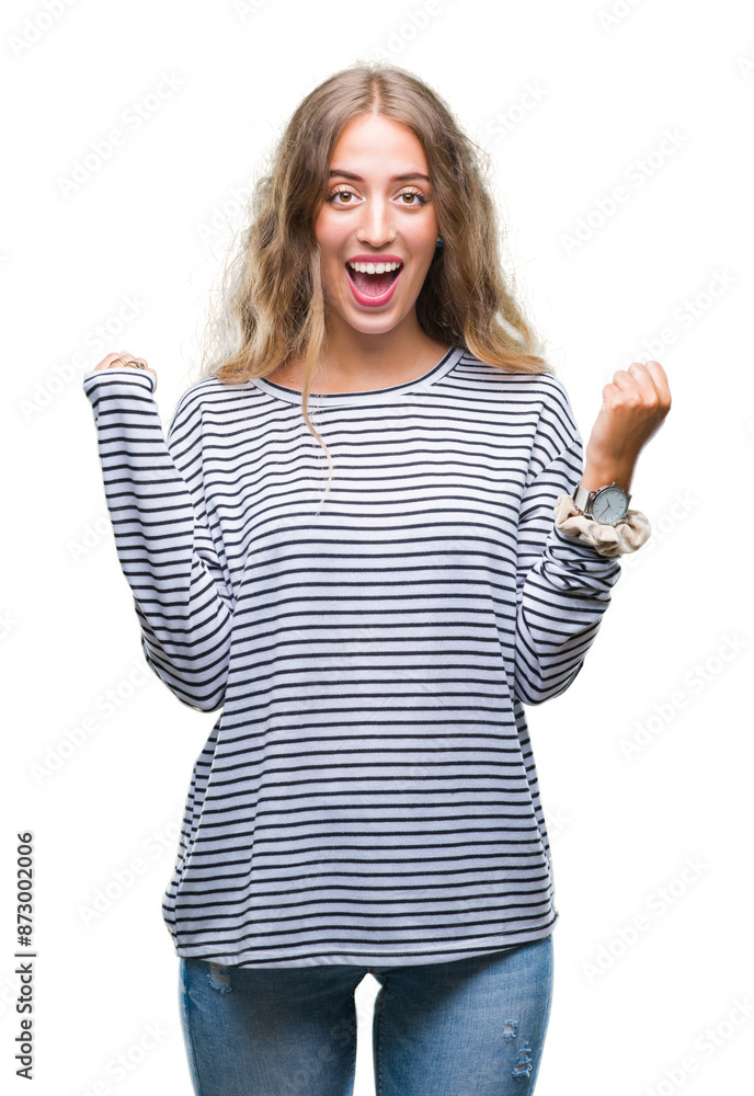 Beautiful young blonde woman wearing stripes sweater over isolated background celebrating surprised and amazed for success with arms raised and open eyes. Winner concept. Beautiful young blonde woman wearing stripes sweater over isolated background celebrating surprised and amazed for success with arms raised and open eyes. Winner concept.