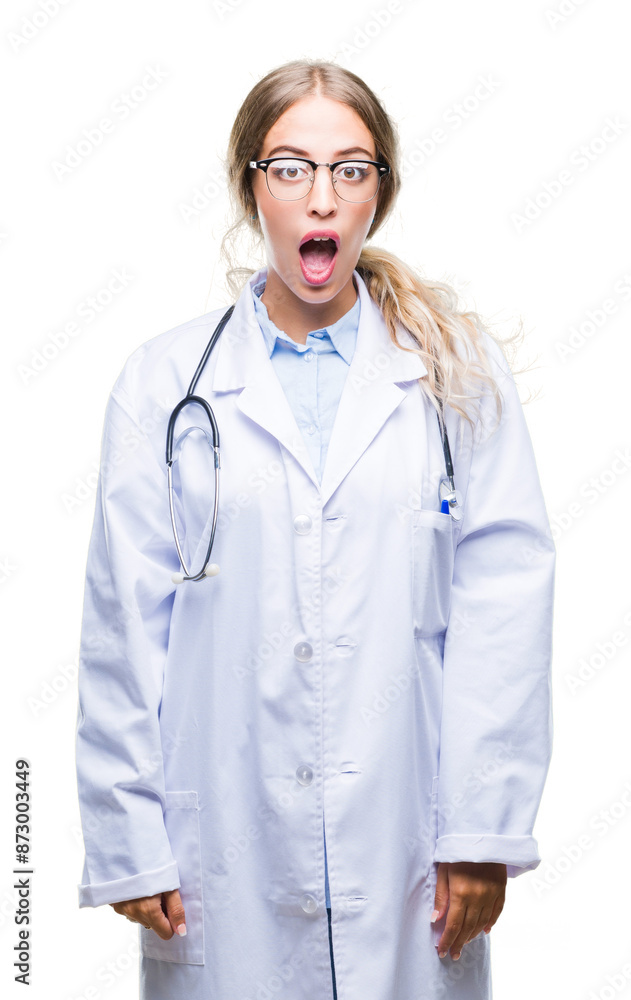 Beautiful young blonde doctor woman wearing medical uniform over isolated background afraid and shocked with surprise expression, fear and excited face. Beautiful young blonde doctor woman wearing medical uniform over isolated background afraid and shocked with surprise expression, fear and excited face.