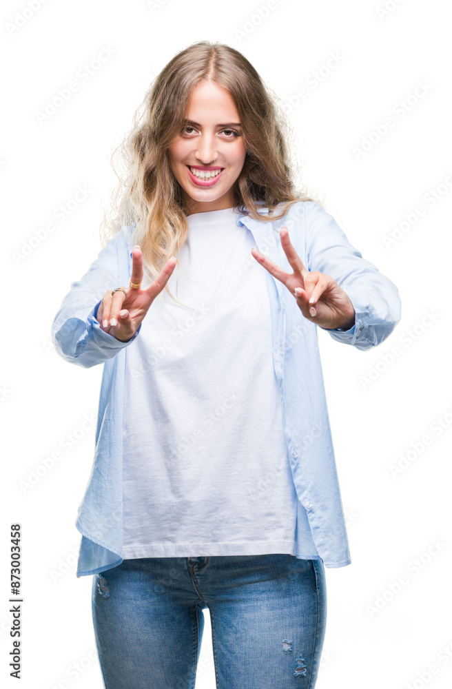 Beautiful young blonde woman over isolated background smiling looking to the camera showing fingers doing victory sign. Number two. Beautiful young blonde woman over isolated background smiling looking to the camera showing fingers doing victory sign. Number two.