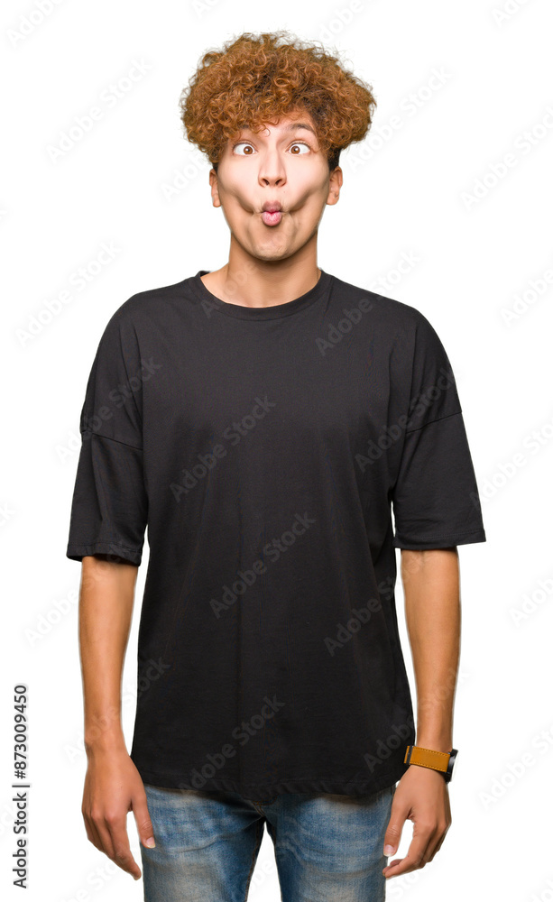 Young handsome man with afro hair wearing black t-shirt making fish face with lips, crazy and comical gesture. Funny expression. Young handsome man with afro hair wearing black t-shirt making fish face with lips, crazy and comical gesture. Funny expression.