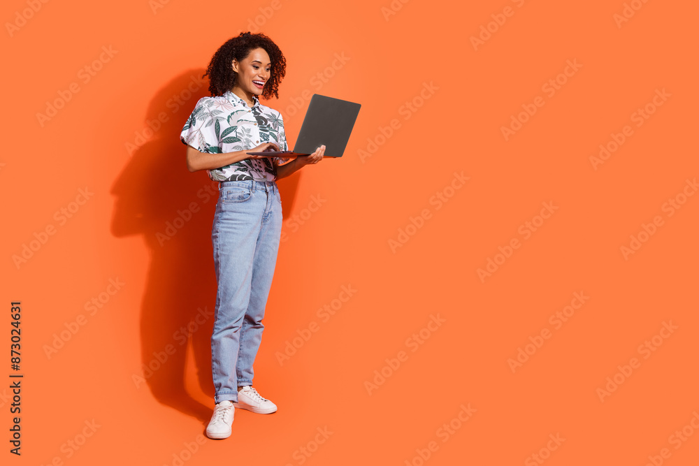 Photo portrait of young junior developer funny woman in summer shirt working distant using computer isolated on orange color background Photo portrait of young junior developer funny woman in summer shirt working distant using computer isolated on orange color background