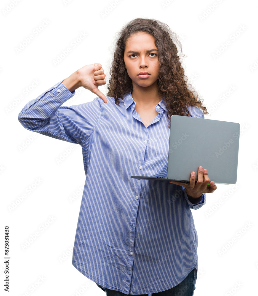 Young hispanic woman holding computer laptop with angry face, negative sign showing dislike with thumbs down, rejection concept Young hispanic woman holding computer laptop with angry face, negative sign showing dislike with thumbs down, rejection concept