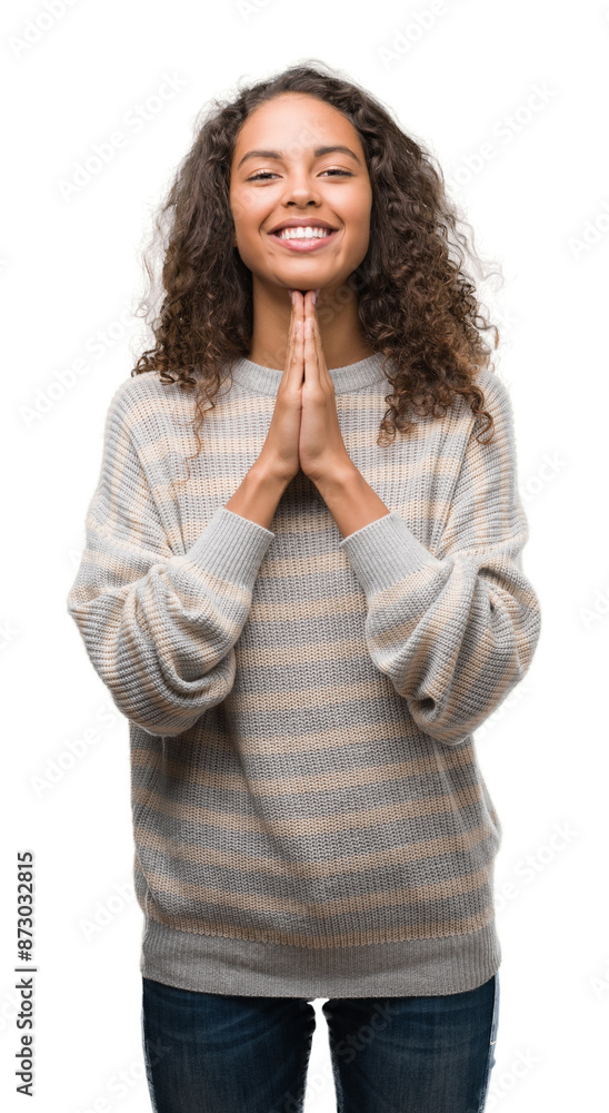 Beautiful young hispanic woman wearing stripes sweater praying with hands together asking for forgiveness smiling confident. Beautiful young hispanic woman wearing stripes sweater praying with hands together asking for forgiveness smiling confident.