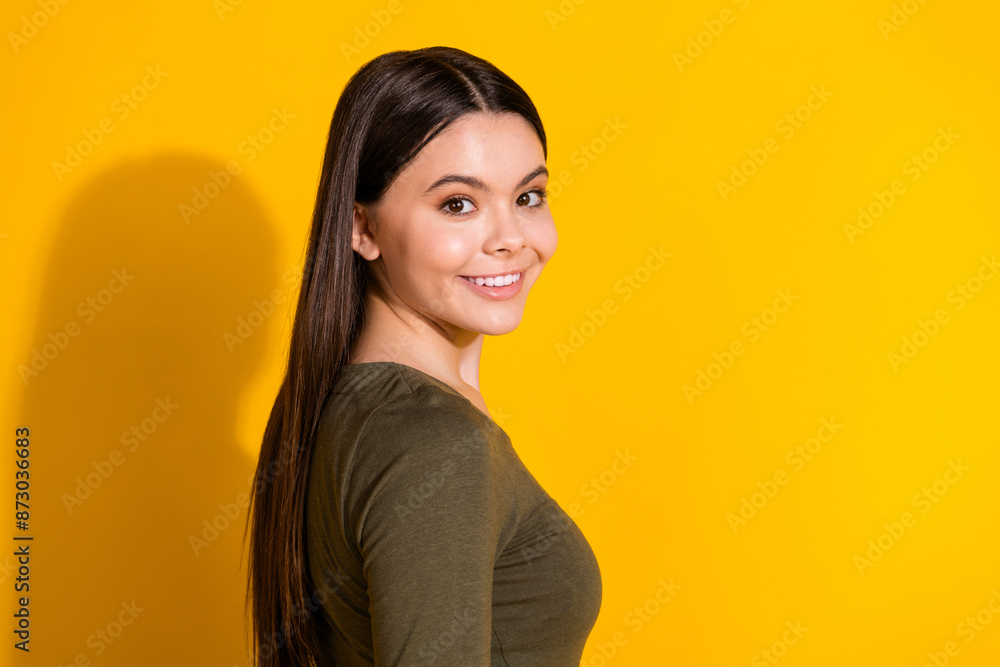 Photo portrait of lovely teen lady turn around cheerful dressed stylish khaki garment isolated on yellow color background Photo portrait of lovely teen lady turn around cheerful dressed stylish khaki garment isolated on yellow color background
