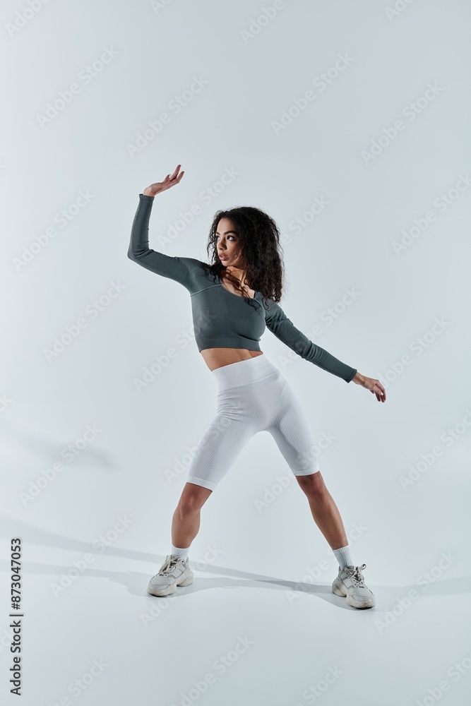 A young African American woman in workout clothes poses against a white backdrop, showcasing her athleticism and fitness. A young African American woman in workout clothes poses against a white backdrop, showcasing her athleticism and fitness.
