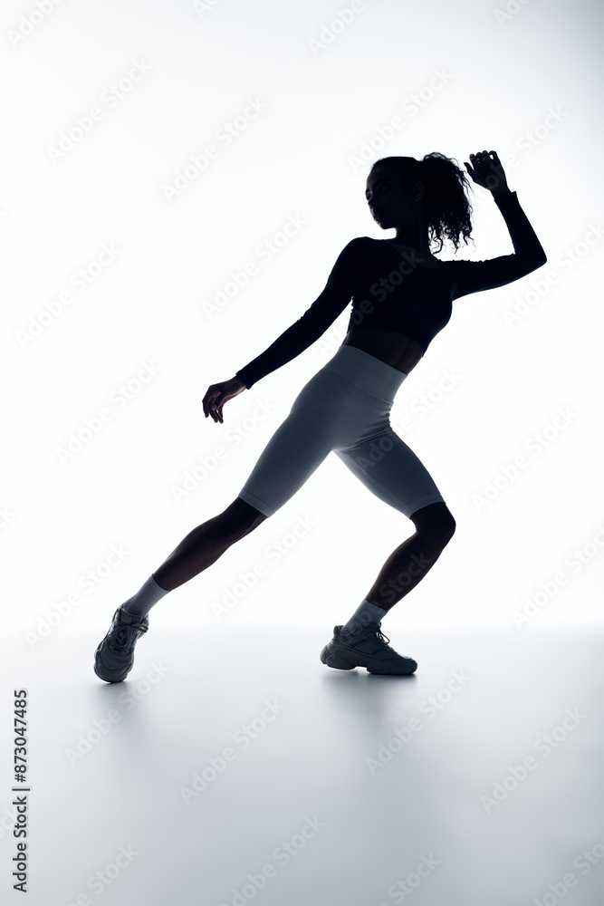 A young woman in athletic wear stretches her leg, silhouetted against a white background.