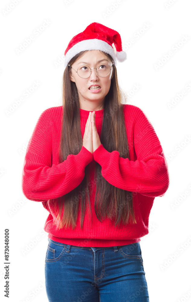 Young Chinese woman over isolated background wearing christmas hat begging and praying with hands together with hope expression on face very emotional and worried. Asking for forgiveness. Young Chinese woman over isolated background wearing christmas hat begging and praying with hands together with hope expression on face very emotional and worried. Asking for forgiveness.