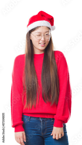 Young Chinese woman over isolated background wearing christmas hat winking looking at the camera with sexy expression, cheerful and happy face.