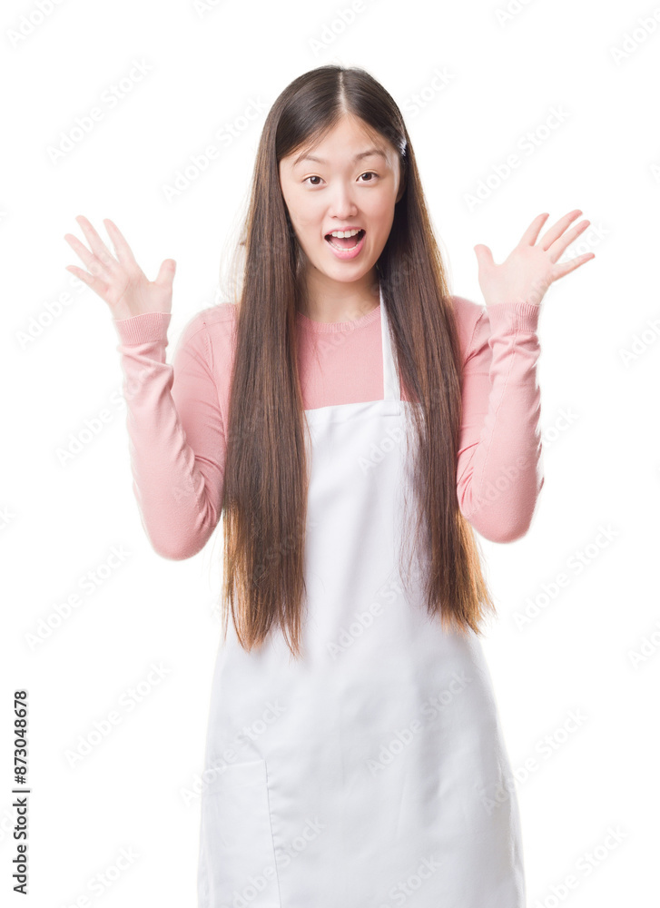 Young Chinese shop owner woman over isolated background wearing white apron very happy and excited, winner expression celebrating victory screaming with big smile and raised hands Young Chinese shop owner woman over isolated background wearing white apron very happy and excited, winner expression celebrating victory screaming with big smile and raised hands